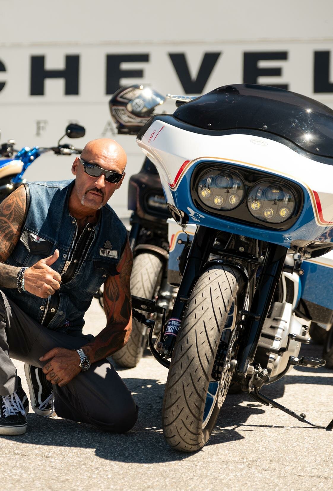 Pilote à côté d'un bagger blanc, bleu et rouge à Courchevel